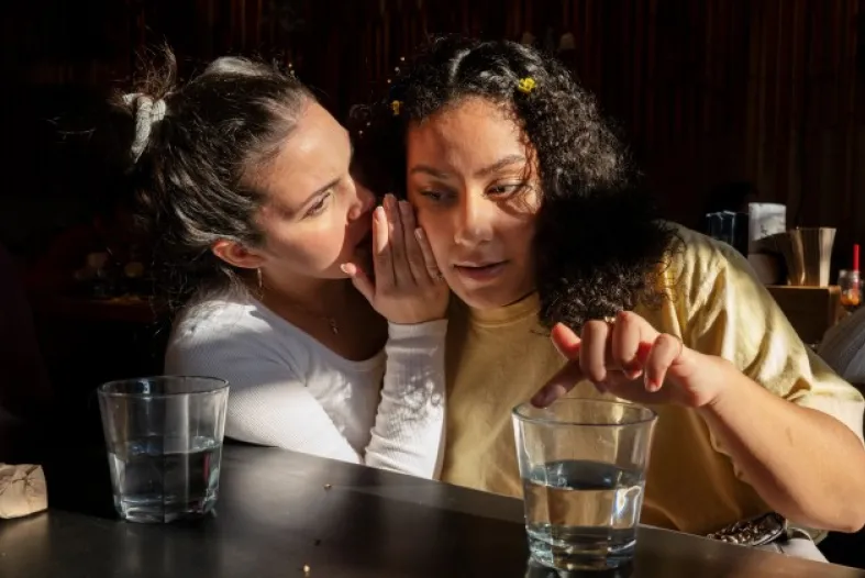 Young girl whispers to adult female