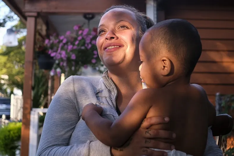 Ashley holds her son Nathaniel on the front porch